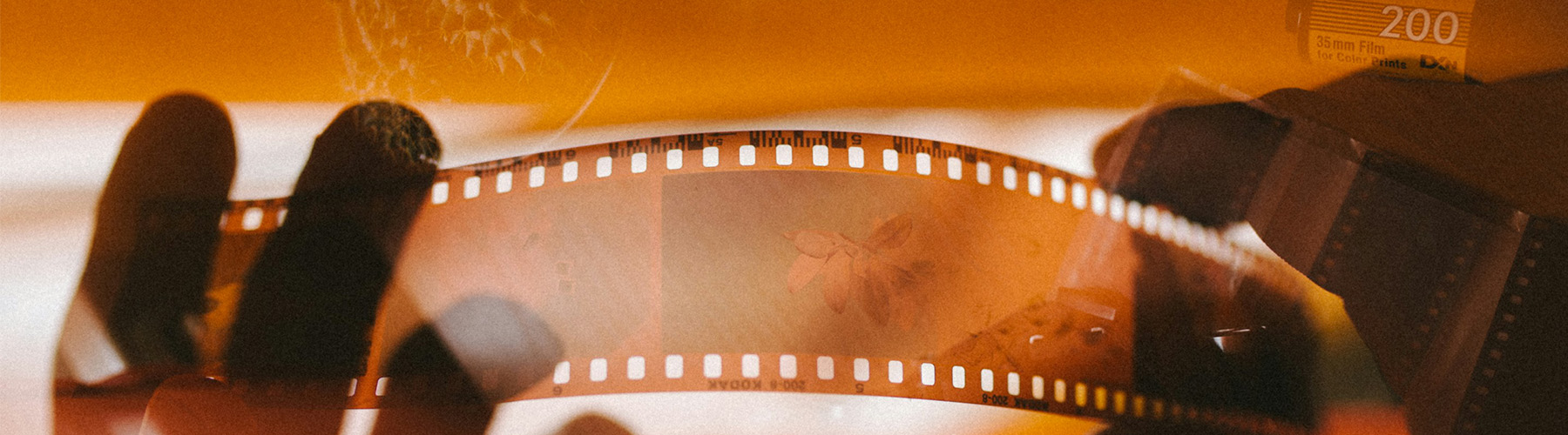 Photo overlaid with other images. Features hands holding a strip of photo negatives in the light.